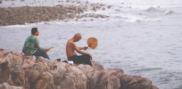 海边岩石上的游客背景图片