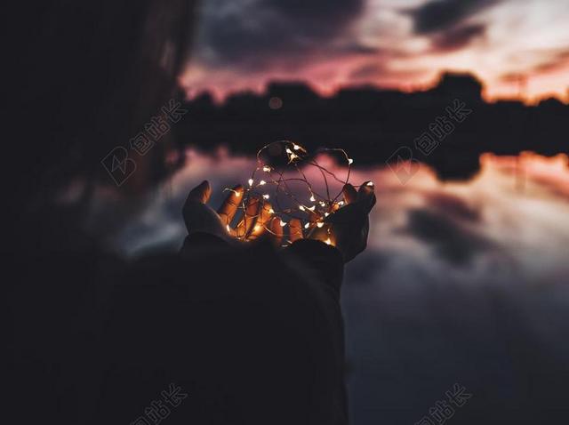 夜晚女人手中的彩灯背景图片