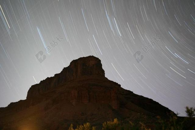 黑色的山岩和旋转的星空背景图片