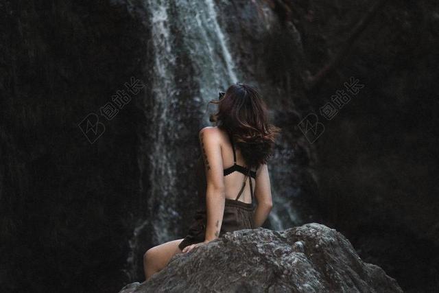 岩石上的黑发女人背景图片