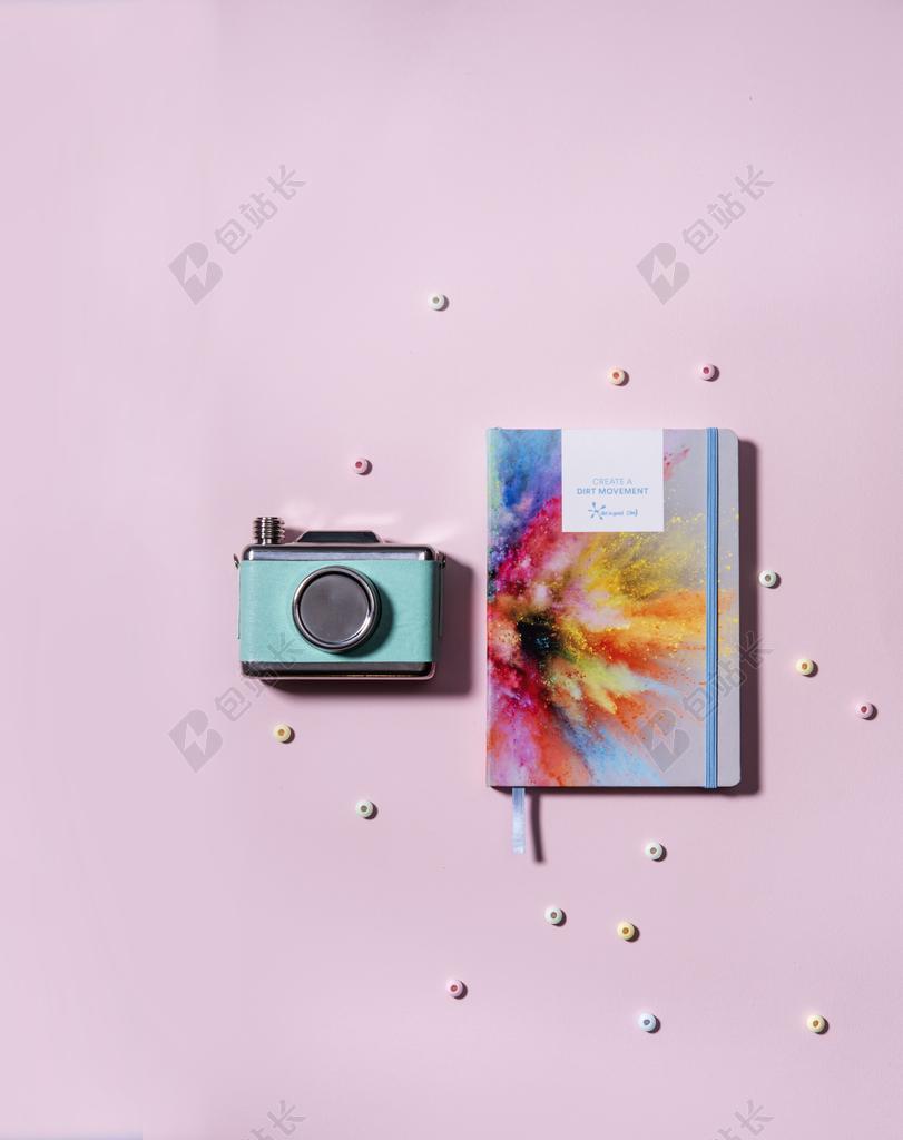 桌子上彩色的本子和老式的相机背景图片